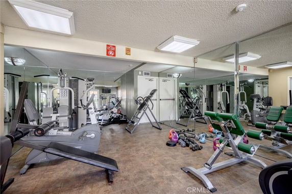 Indoor gym with various exercise equipment and mirrors.