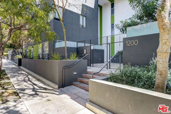 Front view of a modern multi-story building with a stairway entrance and number 1200 on the wall.