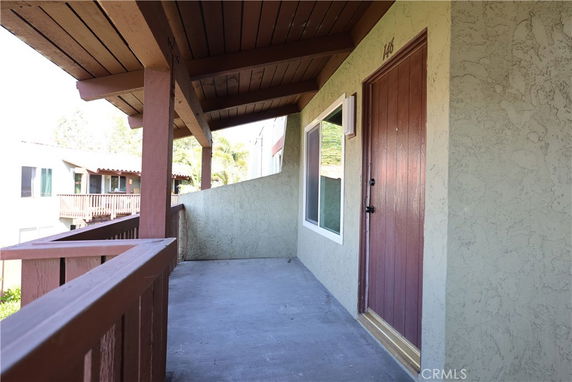 View of the building entrance with a wooden railing and a covered walkway.