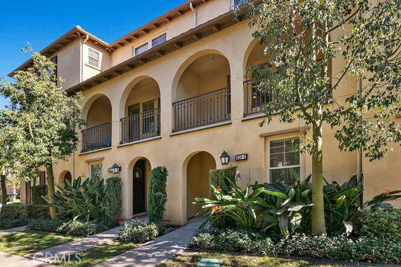 Front view of a two-story house with arched balconies and a stucco finish.