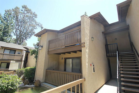 Front view of a multi-level apartment building with exterior stairs and a small balcony.