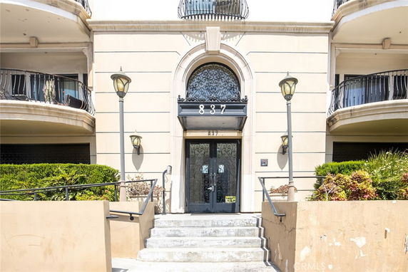 Front view of a building entrance with decorative railings and archway.