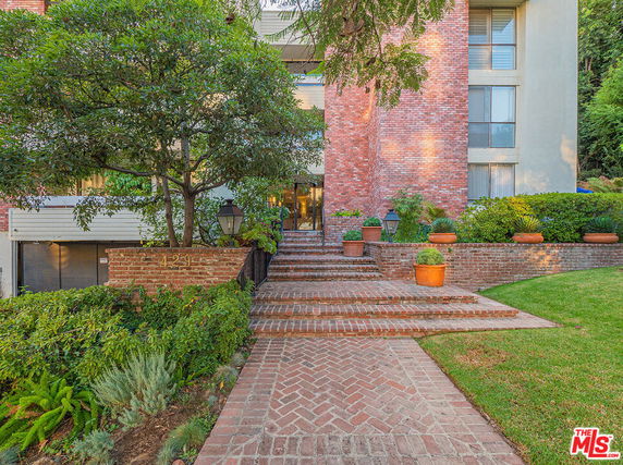 Front view of a multi-story building with brick exterior and landscaped entrance.