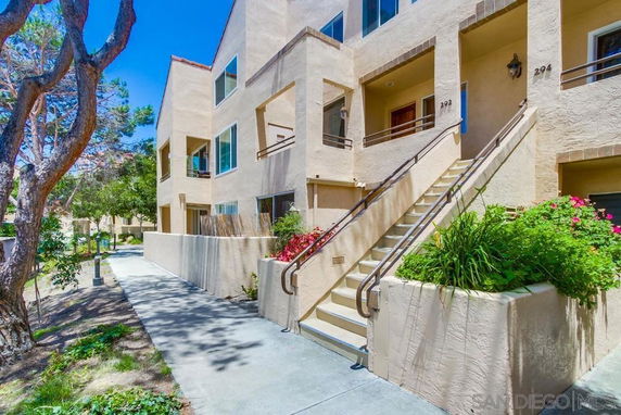 Front view of a multi-story apartment building with stairs leading to the entrance.