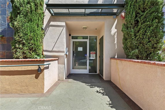Entrance to a modern building with a glass door and surrounding walls.