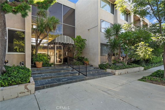 Front view of a multi-story building with large windows and entry steps.