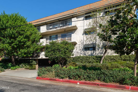 Front view of a multi-story building with balconies and a tiled roof.