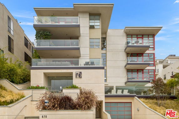 Front view of a modern multi-story residential building with glass balconies.
