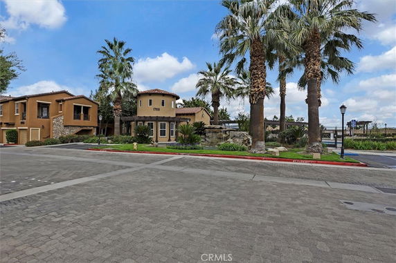 Front view of a residential building with palm trees and stone accents.