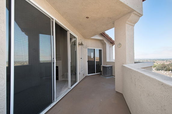 A balcony area with sliding glass doors, overlooking a distant cityscape.