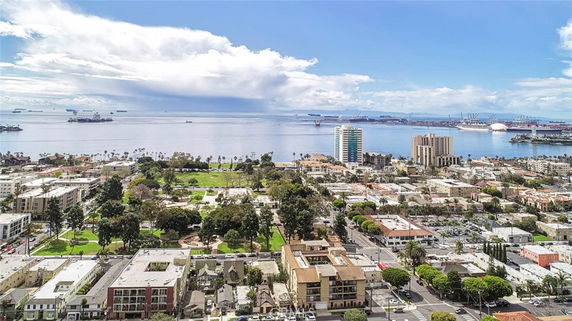 Panoramic view of a coastal city with buildings, park, and ocean in the background.