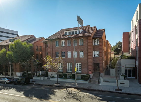 Front view of a multi-story brick building with a prominent sign on the roof.