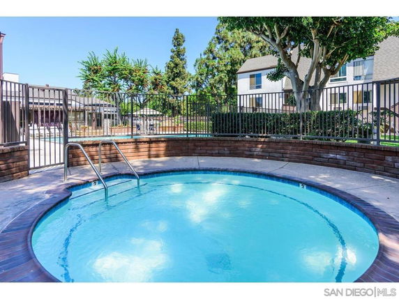 Outdoor view of a round swimming pool with surrounding fence and nearby buildings.