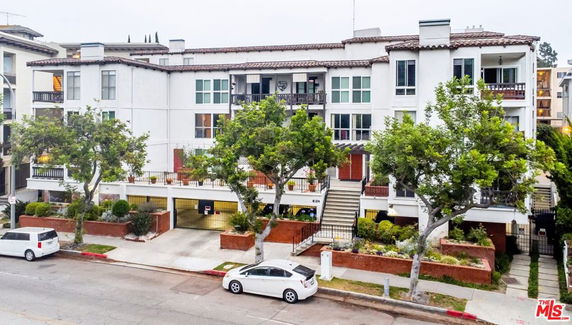 Front view of a multi-story residential building with balconies and a central staircase.
