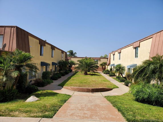 Front view of a two-story building with brown trim and a pathway leading through landscaped grass.