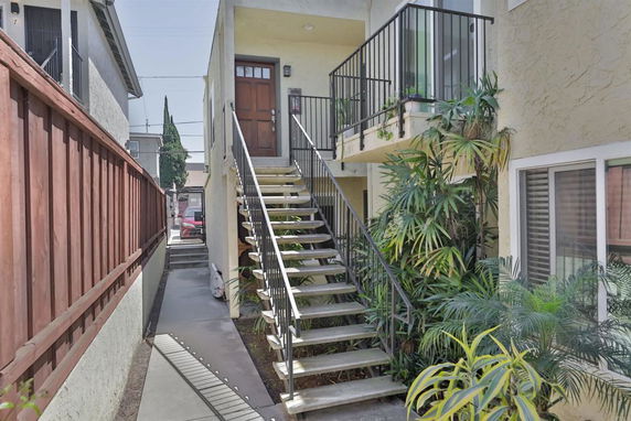 Front view of a building with external stairs and a front door on the first floor.