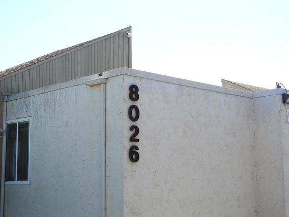 Front view of a building with a visible corner, window, and address number 8026.