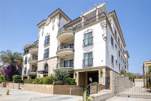 Front view of a multi-story building with balconies and decorative elements.