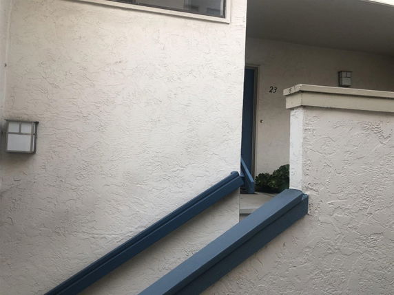 Front view of a building entrance with stairs leading up to a door, numbered 23.