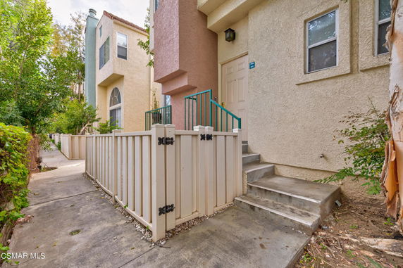 Front view of a multi-story townhouse with a small front patio and stairway entrance.