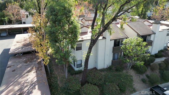 Aerial view of a residential complex with multiple buildings, surrounded by trees and shrubs.