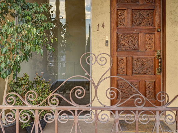 Front view of a house entrance with a decorative wooden door and wrought iron gate.