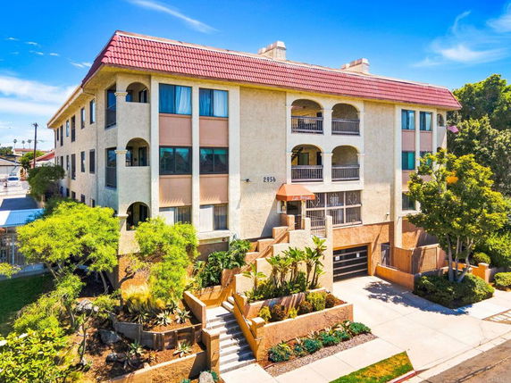 Front view of a multi-story building with balconies and a red-tiled roof.