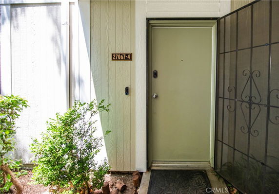 Front view of a building entrance with a solid door and a metal security screen door.