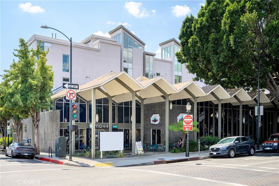 Front view of a multi-story building with large windows and a distinctive roof design.