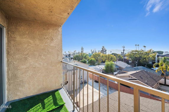 View from a balcony showing rooftops and distant landscape.