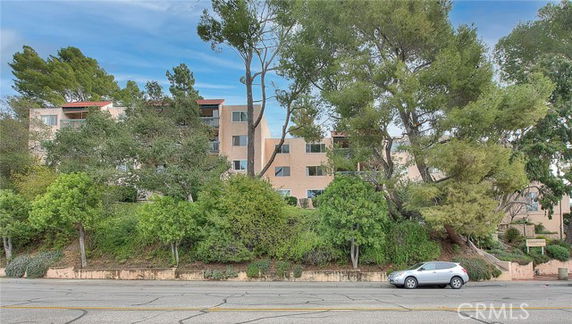 Front view of a multi-story residential building surrounded by trees.