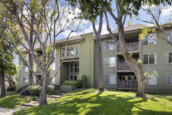 Front view of a three-story apartment building with balconies and large windows.