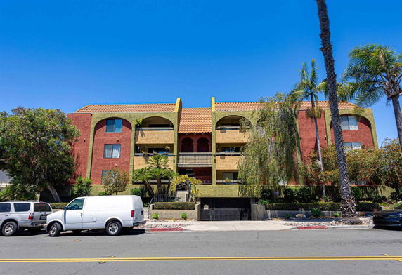 Front view of a multi-story building with balconies and a tiled roof.