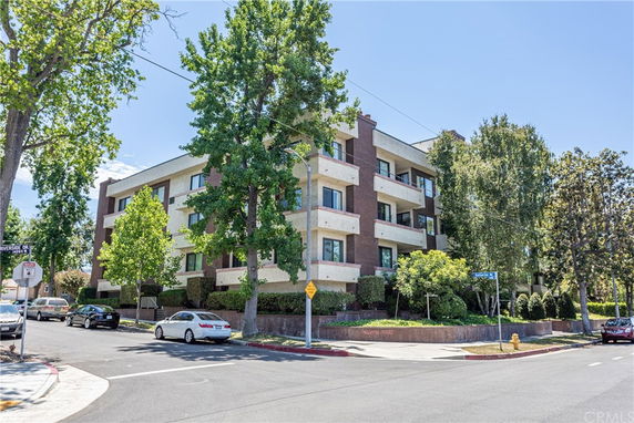 Front view of a multi-story apartment building on a street corner.