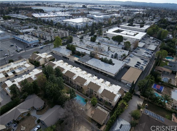 Aerial view of residential and commercial buildings with a swimming pool visible.