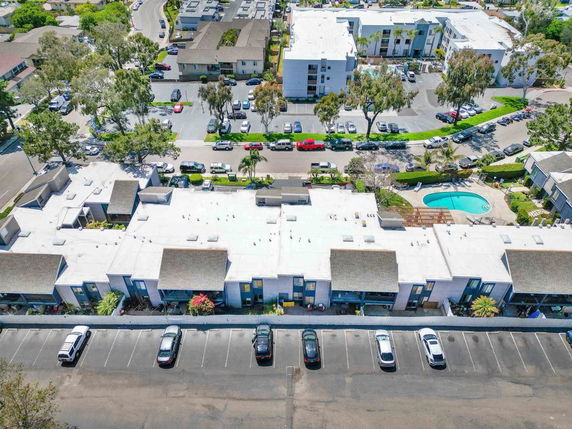 Aerial view of residential buildings and community with parking area and swimming pool.