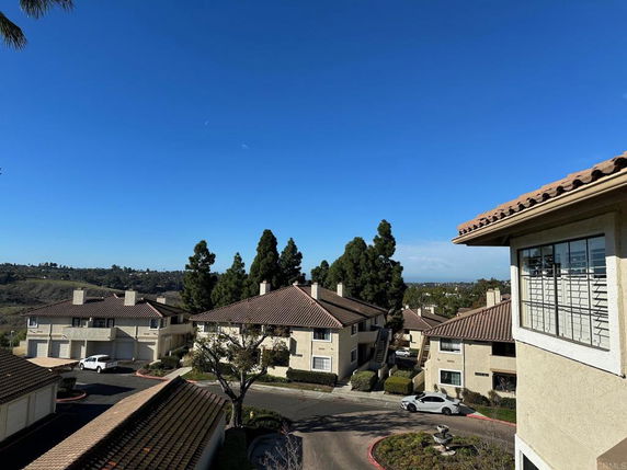 View of residential buildings with sloped roofs and surrounding greenery.