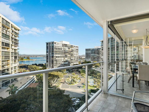 Panoramic view from a balcony showing high-rise buildings and a body of water in the background.