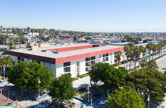 Front view of a large, rectangular building with a red roof and white exterior.