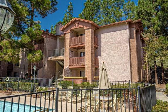 Front view of a multi-story building with balconies and outdoor seating area.
