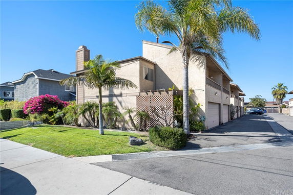 Front view of a two-story house with attached garages and palm trees.