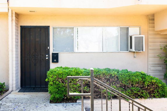 Front view of a building entrance with a metal door and window.