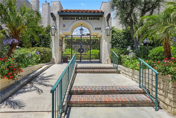 Entrance view of a building with an ornate gate and brick steps.