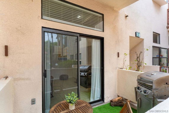 Patio area with sliding glass door, outdoor grill, and small table with plant.