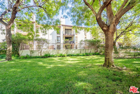 Front view of a multi-story residential building with balconies and a landscaped garden.