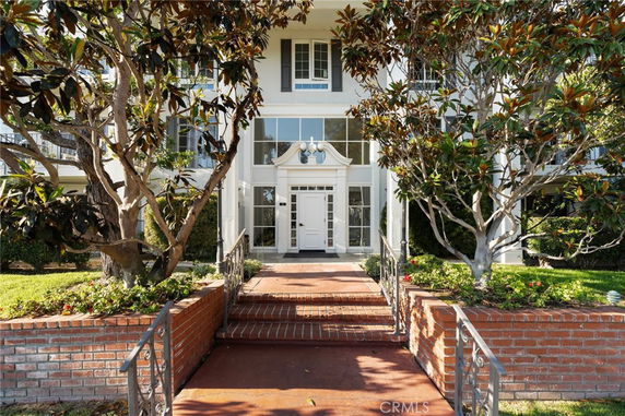 Front view of a multi-story house with a decorative entrance and brick pathway.
