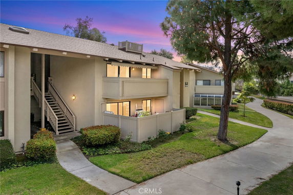 Front view of a two-story residential building with balconies and exterior stairs.