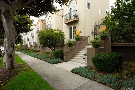 Front view of a multi-story residential building with stairs leading to the entrance.