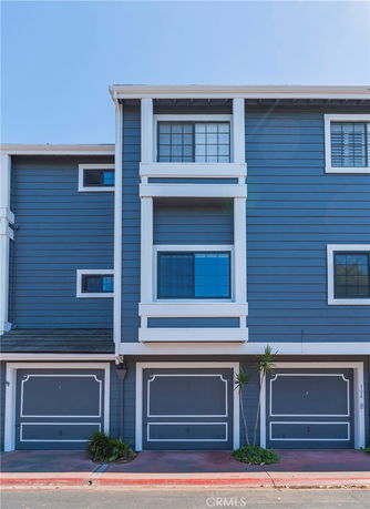 Front view of a blue multi-story house with two garages.