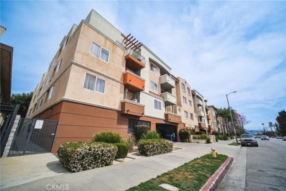 Front view of a multi-story apartment building with balconies and gated entrance.